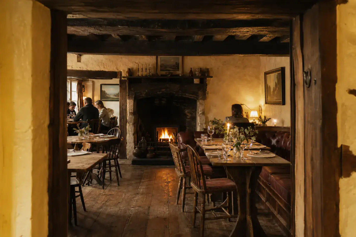 Historic country inn dining room with old oak tables and a glowing fireplace