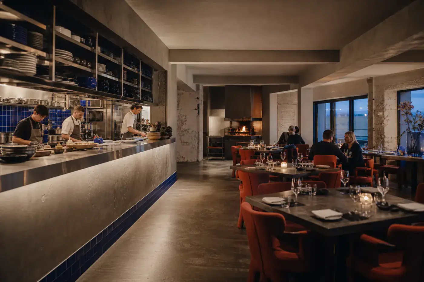 Modern seafood bar with an open kitchen, cobalt tiles and rust-coloured chairs